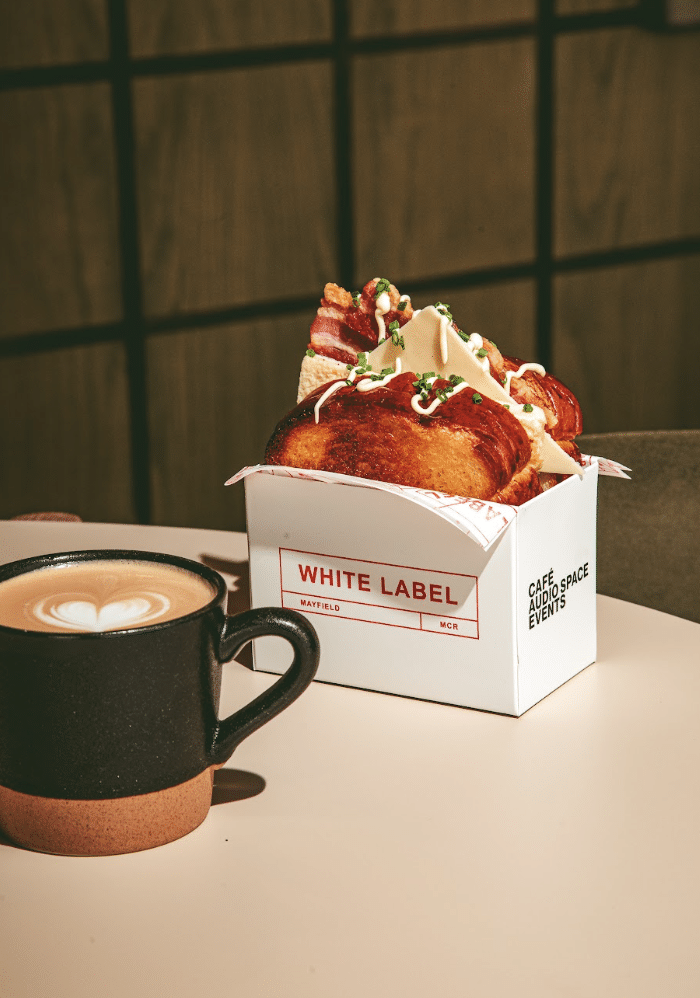 
A new all-day café and cultural space is set to open at Manchester’s Depot Mayfield on Saturday, 26th September, as White Label brings together exceptional coffee, simple food and vinyl culture in one of the city’s most exciting neighbourhoods.

Created at the front door of Mayfield in the iconic Depot Mayfield, White Label is a place to arrive, meet, pause and return to throughout the day. The new café will move naturally from morning coffee and breakfast to lunch, after-work drinks and an evolving programme of music and events.

At the heart of White Label is a love of music and vinyl culture, taking inspiration from Manchester’s long relationship with house music, club culture, DJs and independent record shops. Music at White Label will be curated by Manchester DJ Stu Richards, who brings 20 years of experience spanning jazz, funk, soul, reggae, disco, house, techno and drum and bass.

The name White Label references the plain vinyl pressings traditionally circulated among DJs, record shops and promoters ahead of a track’s official release. Associated with discovery, experimentation and hearing something first, white labels became part of the culture around house and club music, moving new records from producers to DJs and onto dancefloors.

It is a fitting reference for Mayfield. Over recent years, Depot Mayfield has played its own part in Manchester’s cultural story, hosting The Warehouse Project, Manchester International Festival white label 